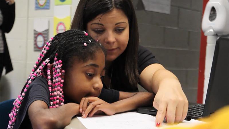 Education student helping child read