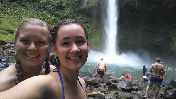 Natalie swimming under a waterfall